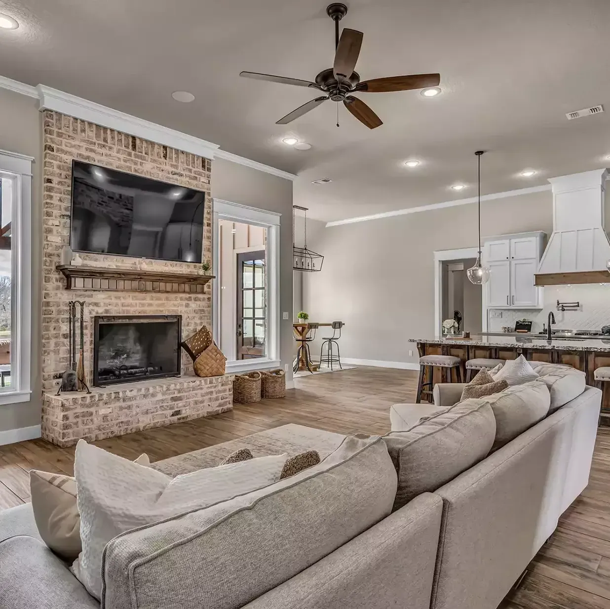 A living room with a couch , fireplace , television and ceiling fan.