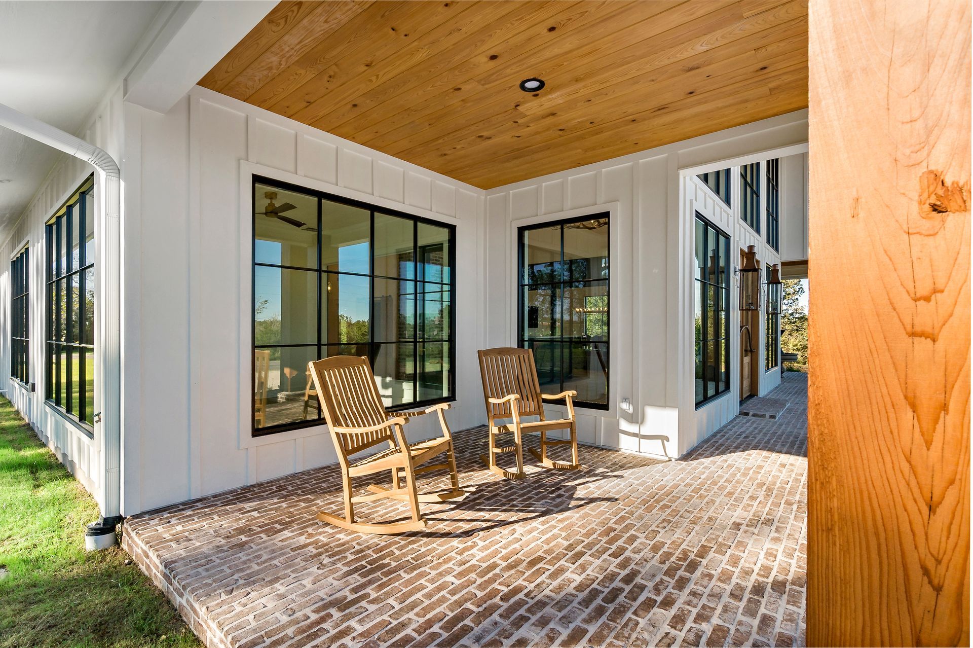 There are two rocking chairs on the porch of a house.