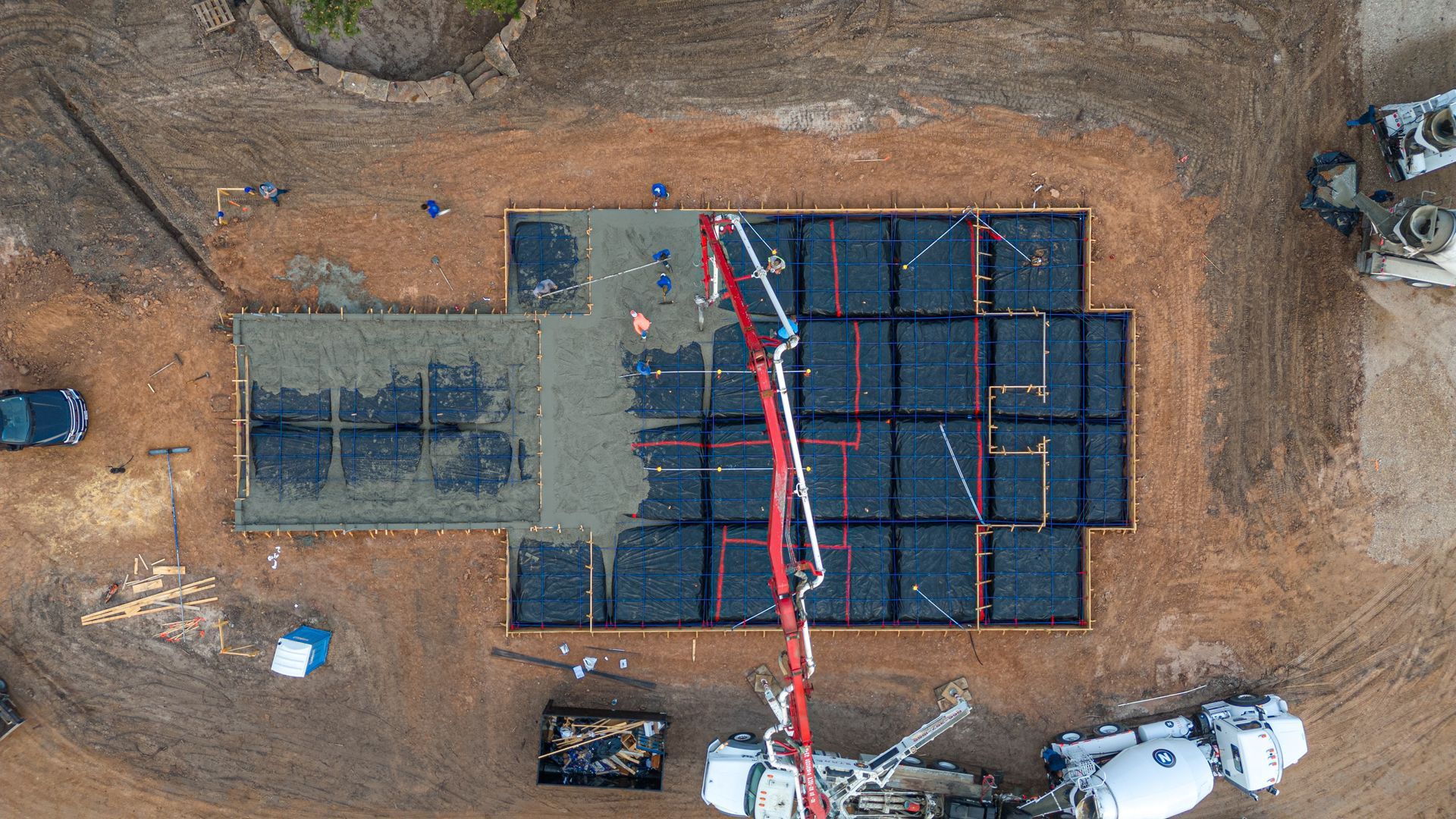 An aerial view of a construction site with a crane pouring concrete.