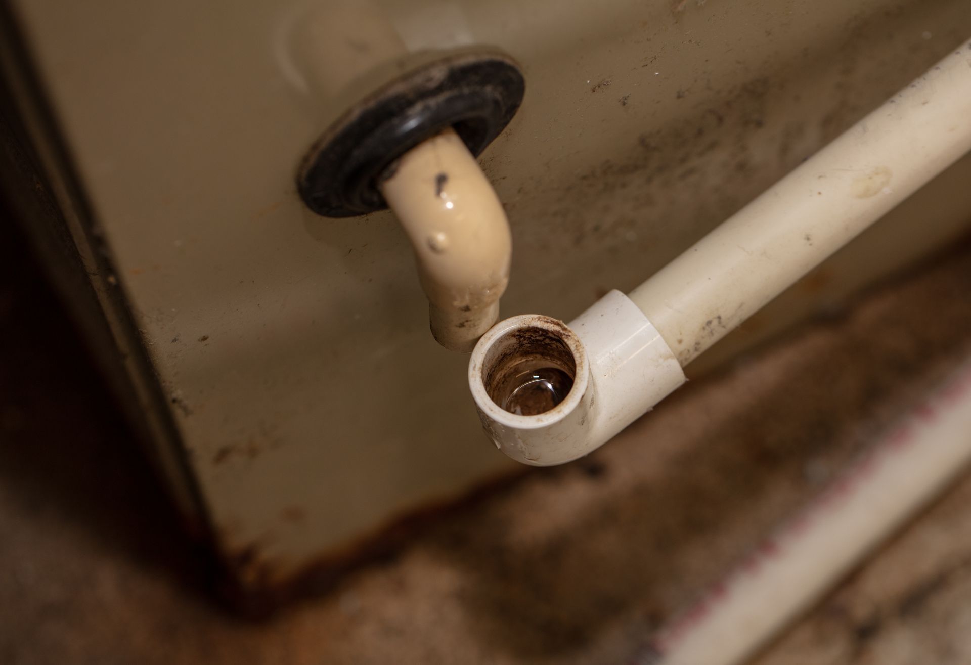 Close-up of a disconnected sink drain pipe. The elbow joint shows brown residue. Close-up of a disconnected sink drain pipe. The elbow joint shows brown residue.