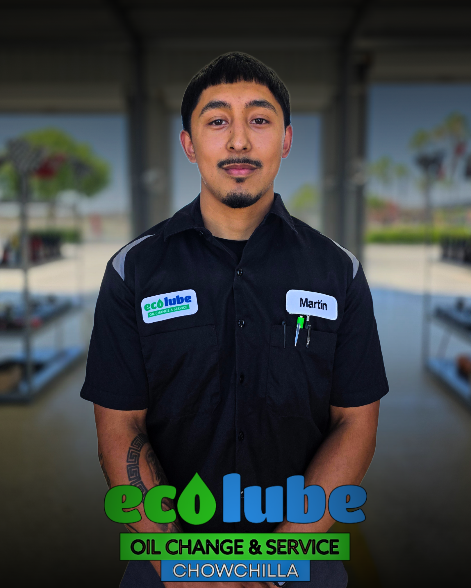Man in uniform at Eco Lube oil change shop with arms crossed. Logo: green and blue "eco Lube" and "OIL CHANGE & SERVICE."