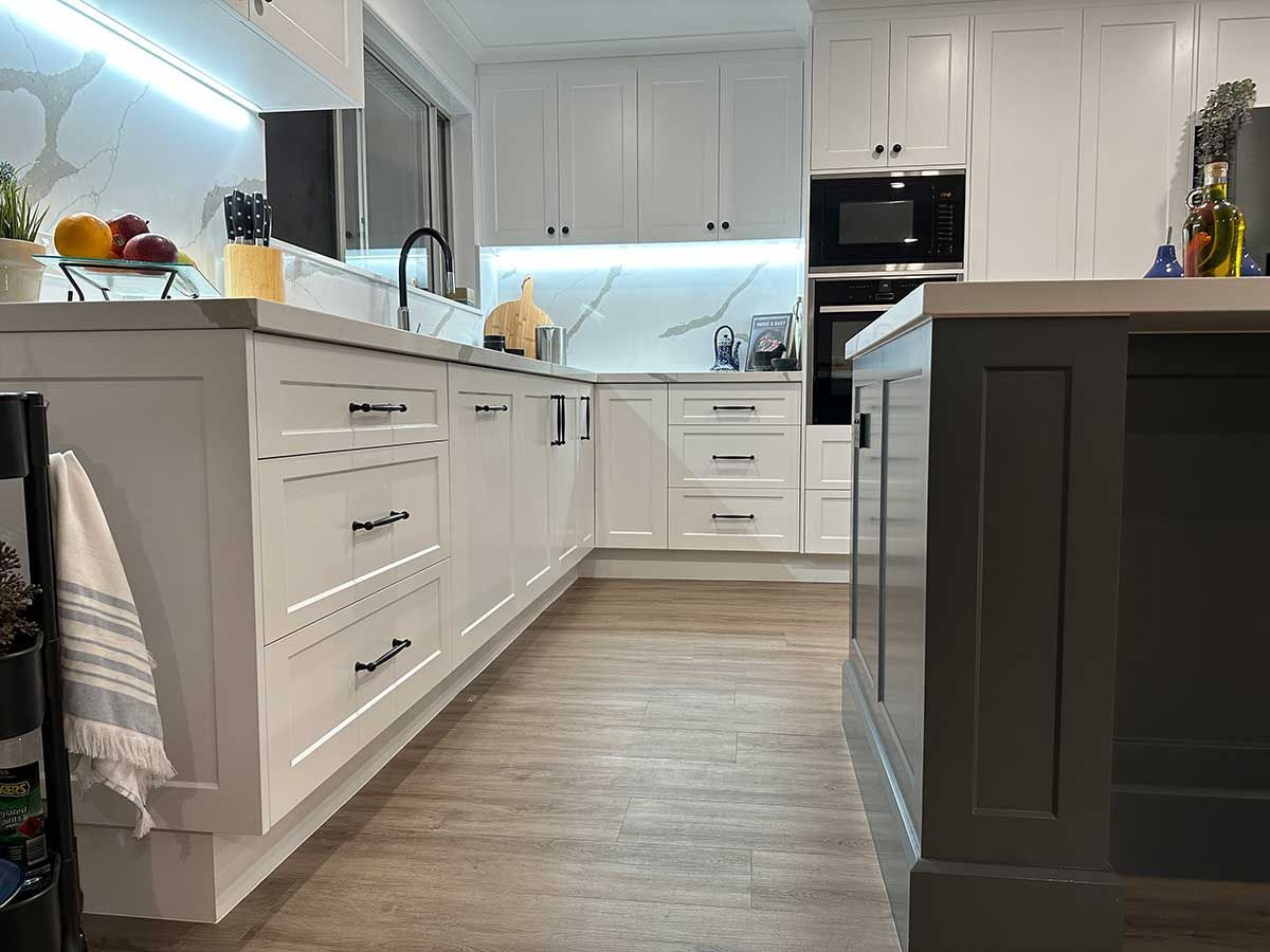 A kitchen with white cabinets and a gray island.