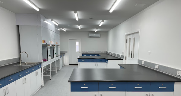 A laboratory with a lot of counters and cabinets and a sink.