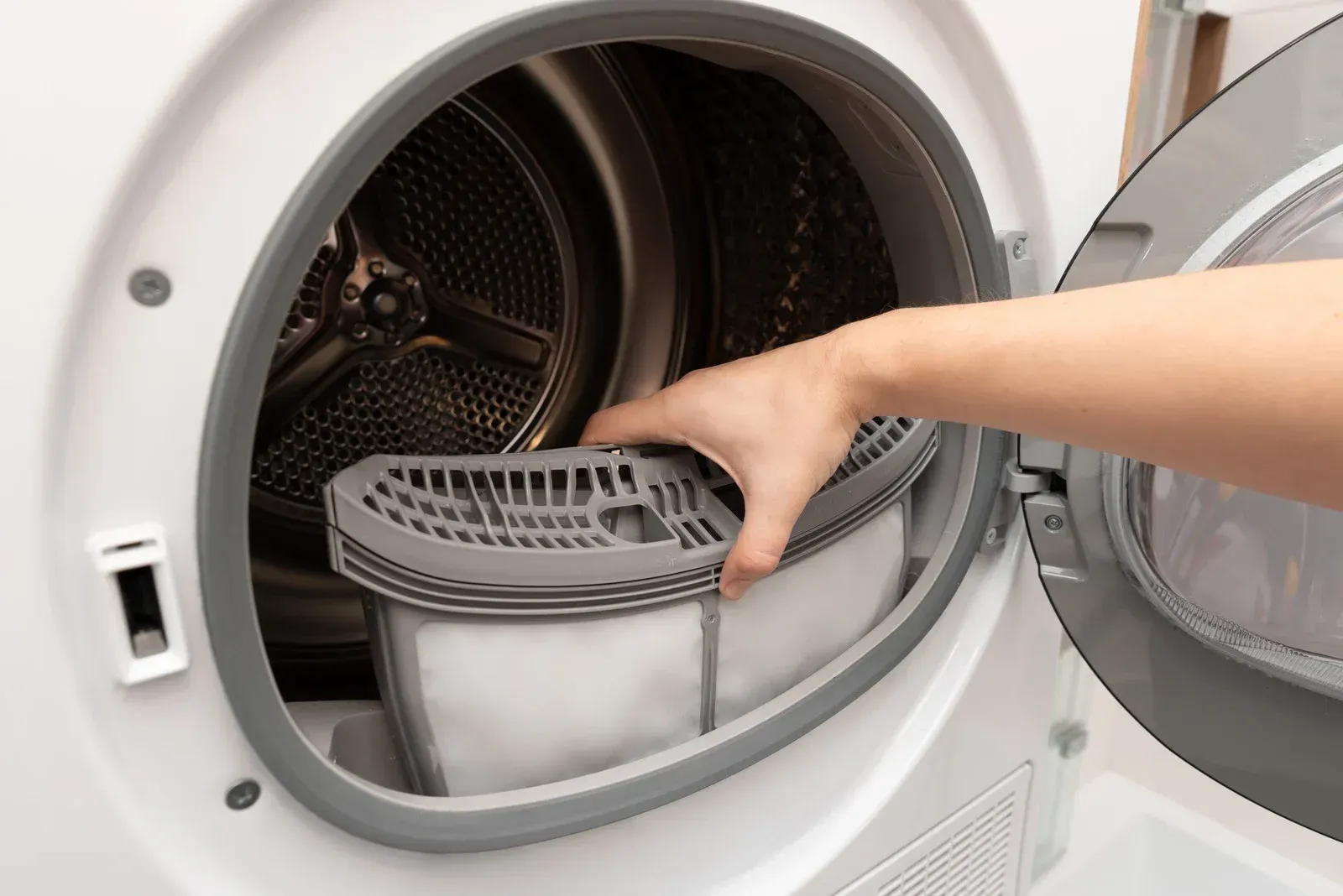 Hand placing a lint filter into an open front-loading dryer
