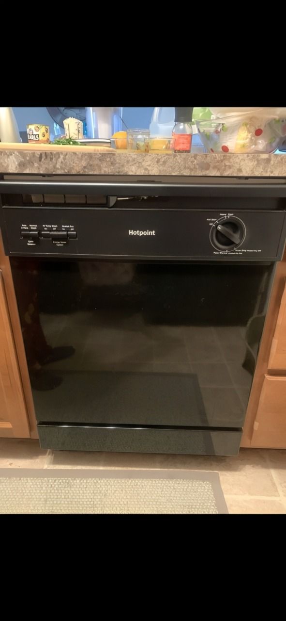 Hands adjusting a dishwasher’s upper rack and center spray arm inside a stainless steel appliance.