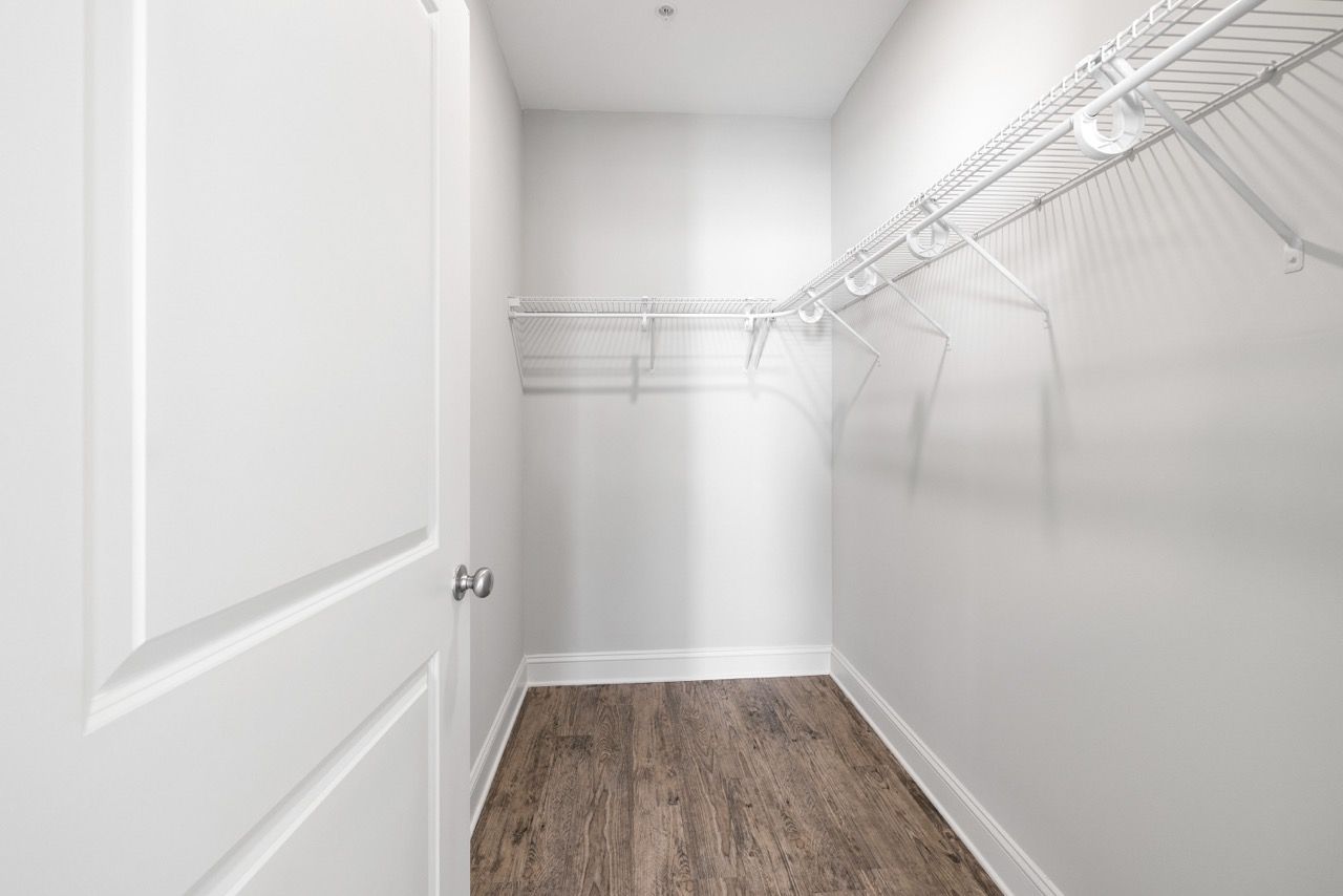 Empty walk-in closet with white wire shelves and wood-look flooring.