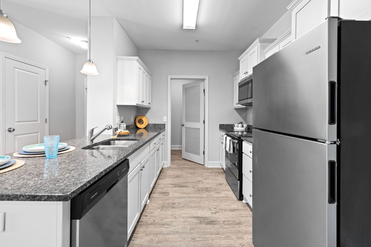 Kitchen in an apartment with white cabinets, granite countertops, and stainless steel appliances.
