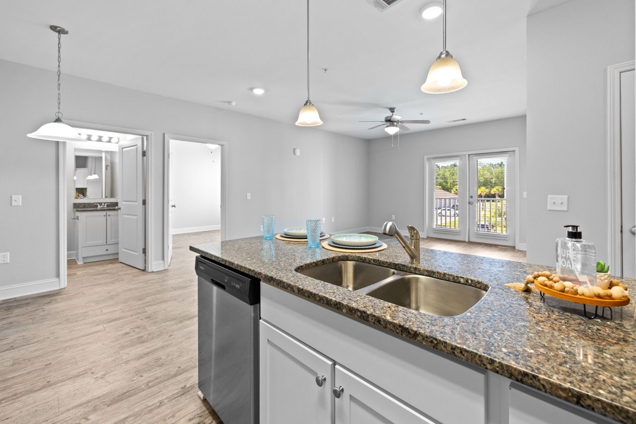Open-concept kitchen with granite island, double sink, and dishwasher.