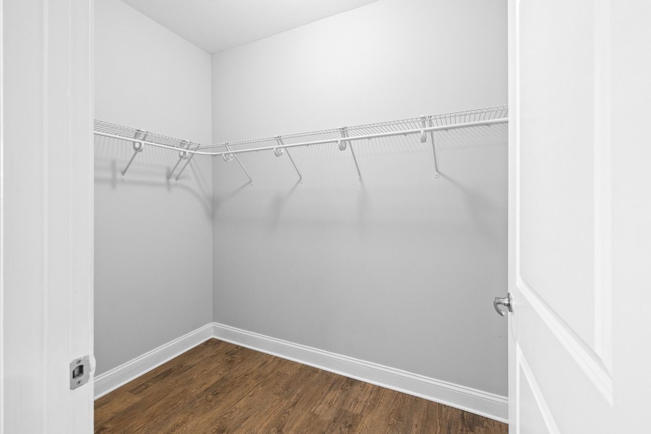 Empty walk-in closet with wire shelving and a wood floor