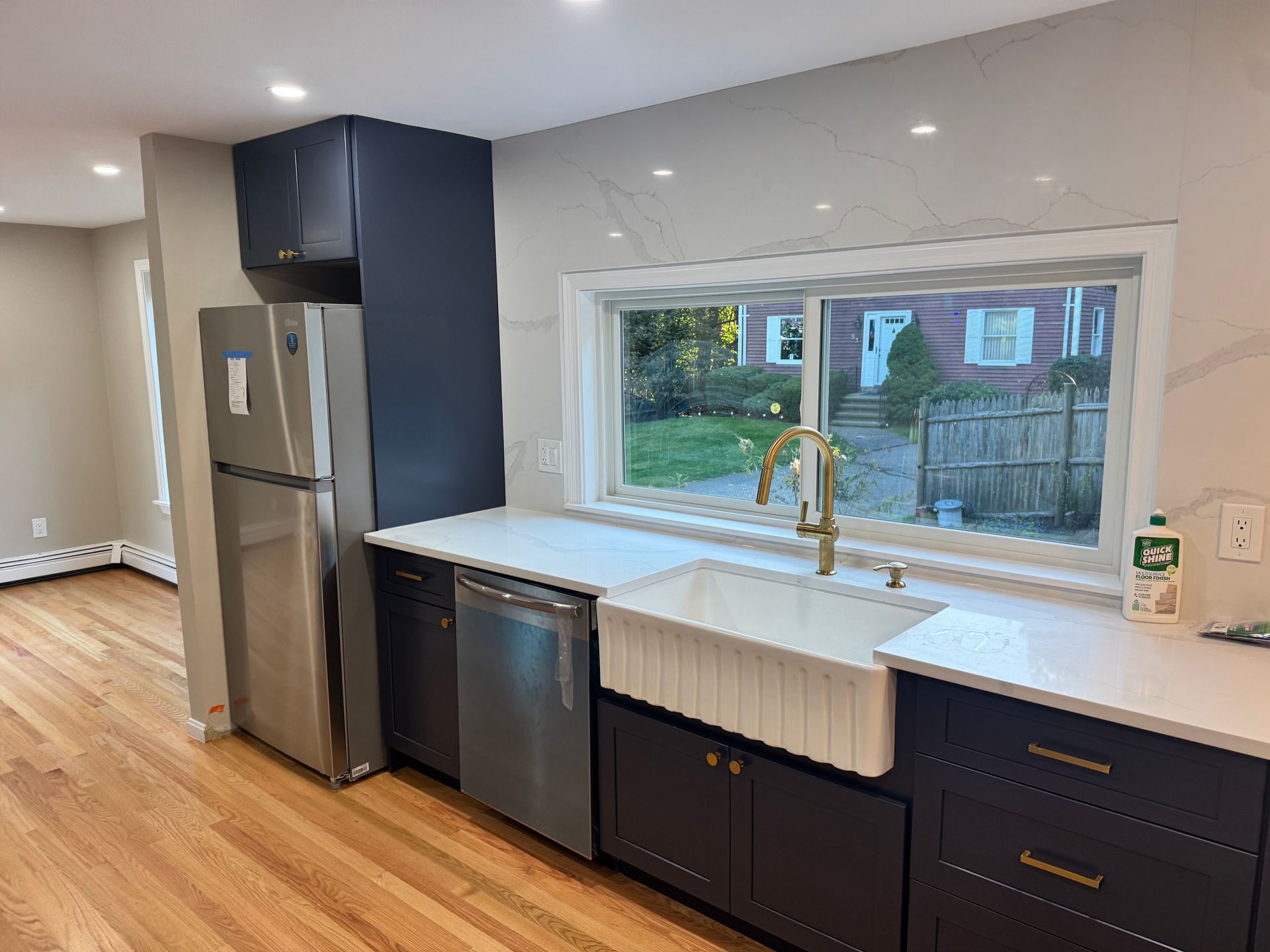 Modern kitchen with navy cabinets, stainless steel appliances, white countertops, and a farmhouse sink.