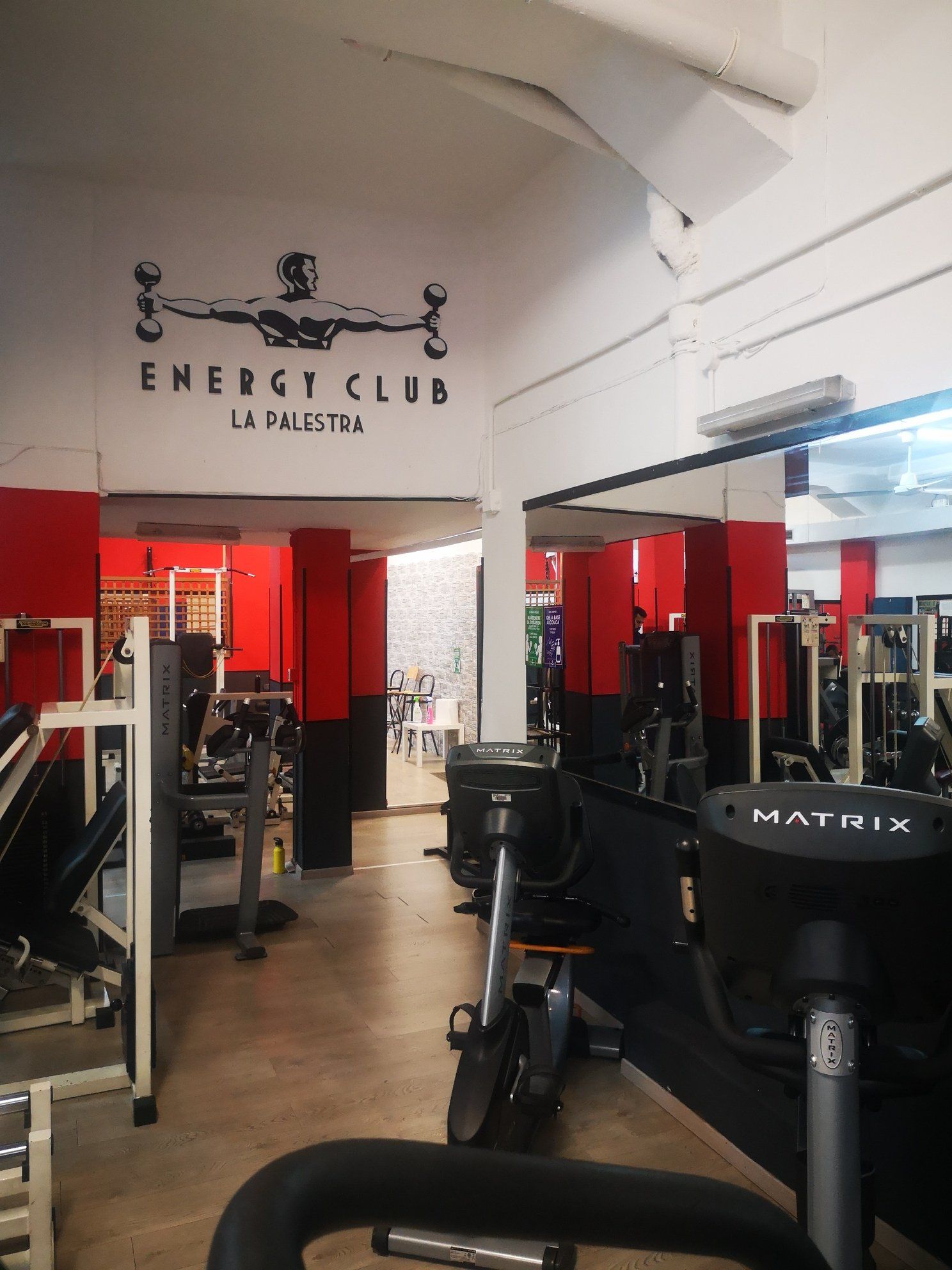 Interno della palestra Energy Club di Palermo con attrezzi ginnici e pareti rosse e bianche.