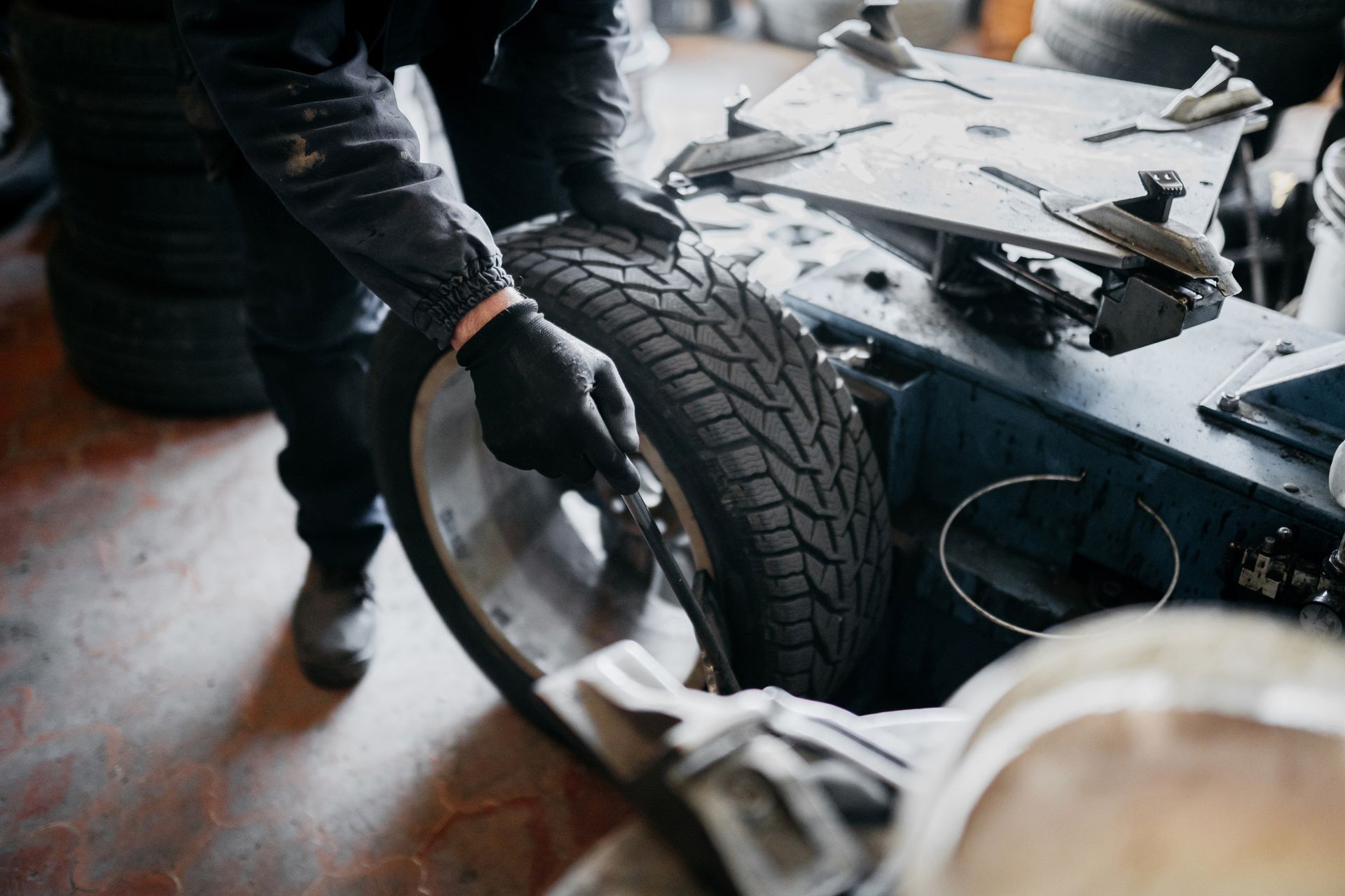 A man is changing a tire on a machine in a garage.