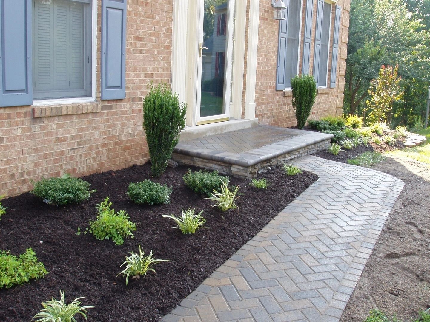 Brick home with a brick path, small garden beds, and blue shutters.