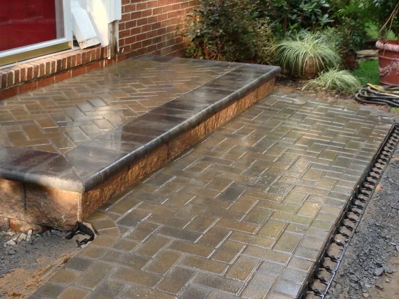 Brick walkway and steps leading to a brick home entrance, wet appearance.