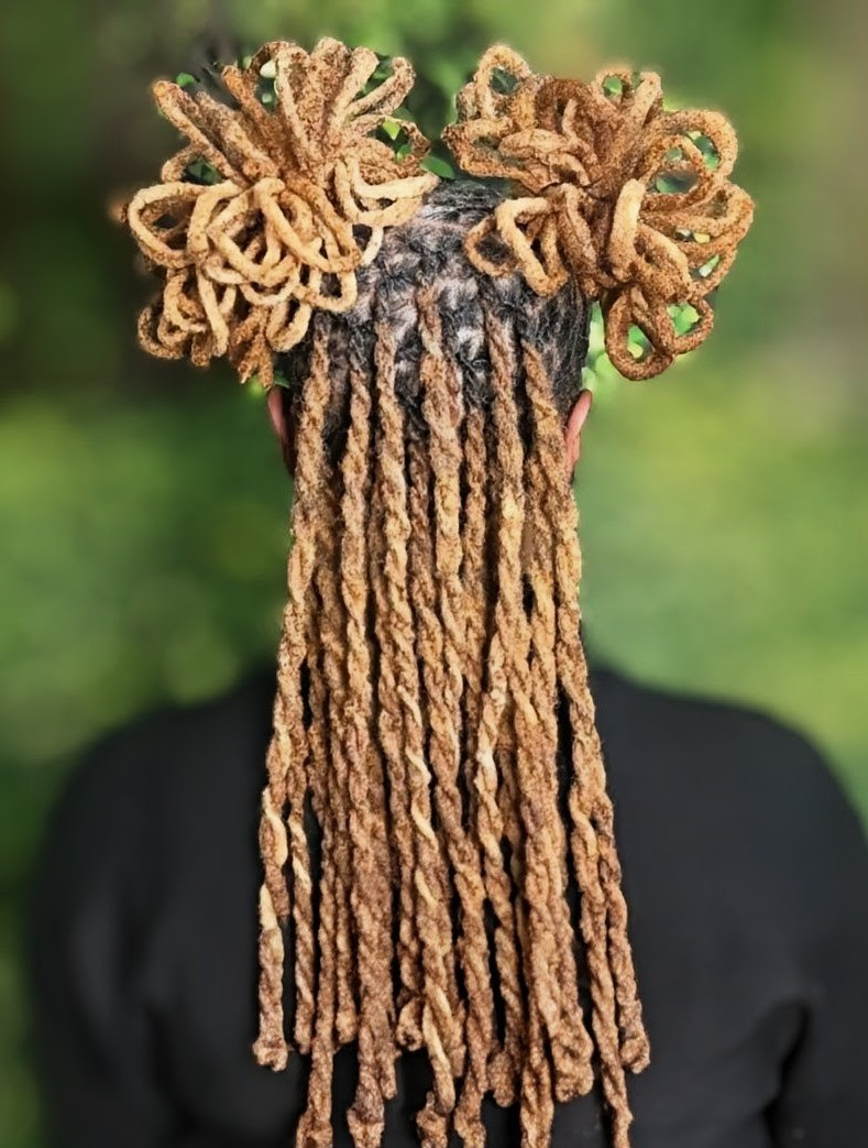 Back view of a person with long, blonde, twisted locs styled in two high, voluminous, circular buns.