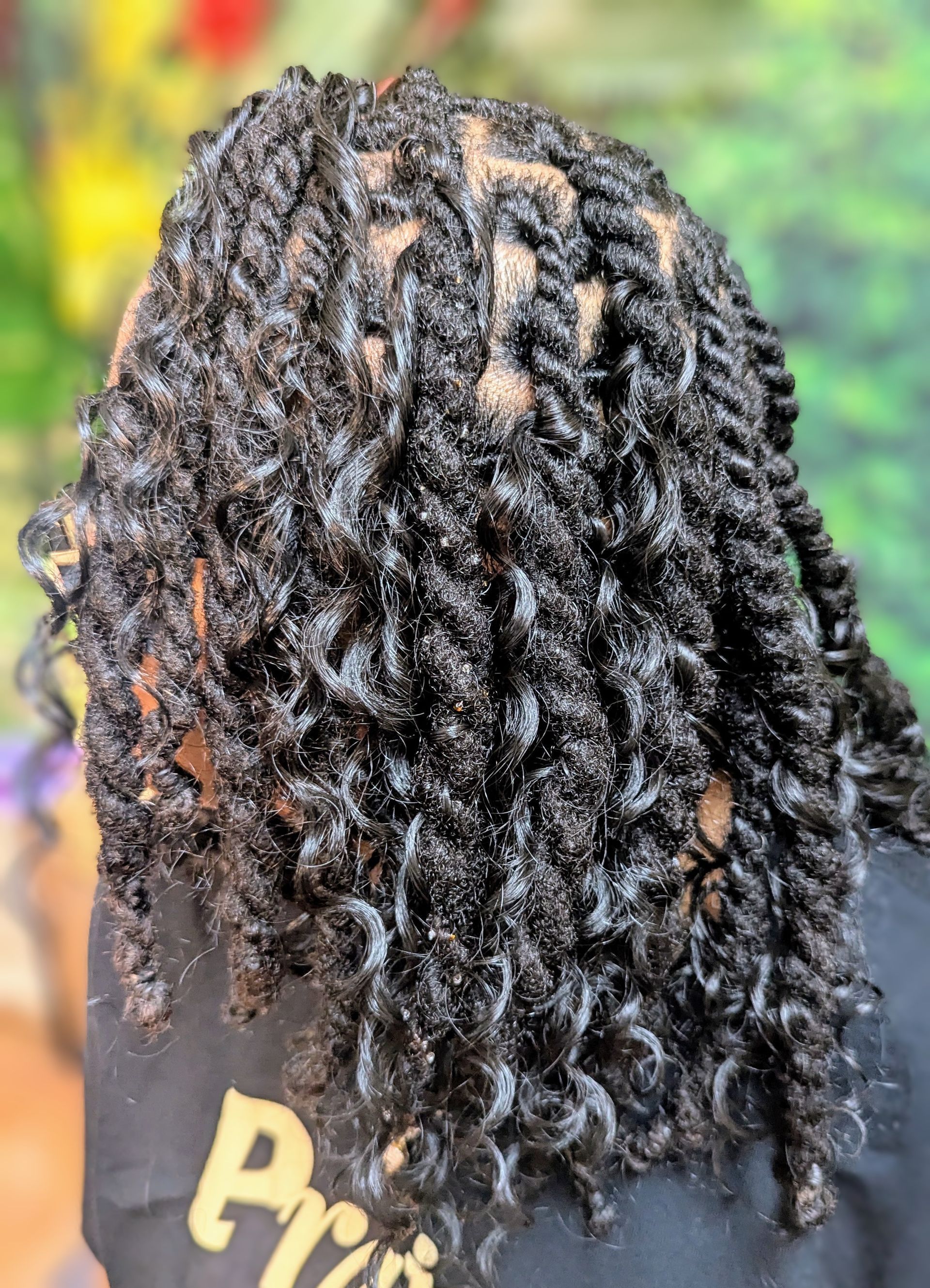 A view from above showing a head of dark, medium-length hair styled in numerous small, textured two-strand twists.