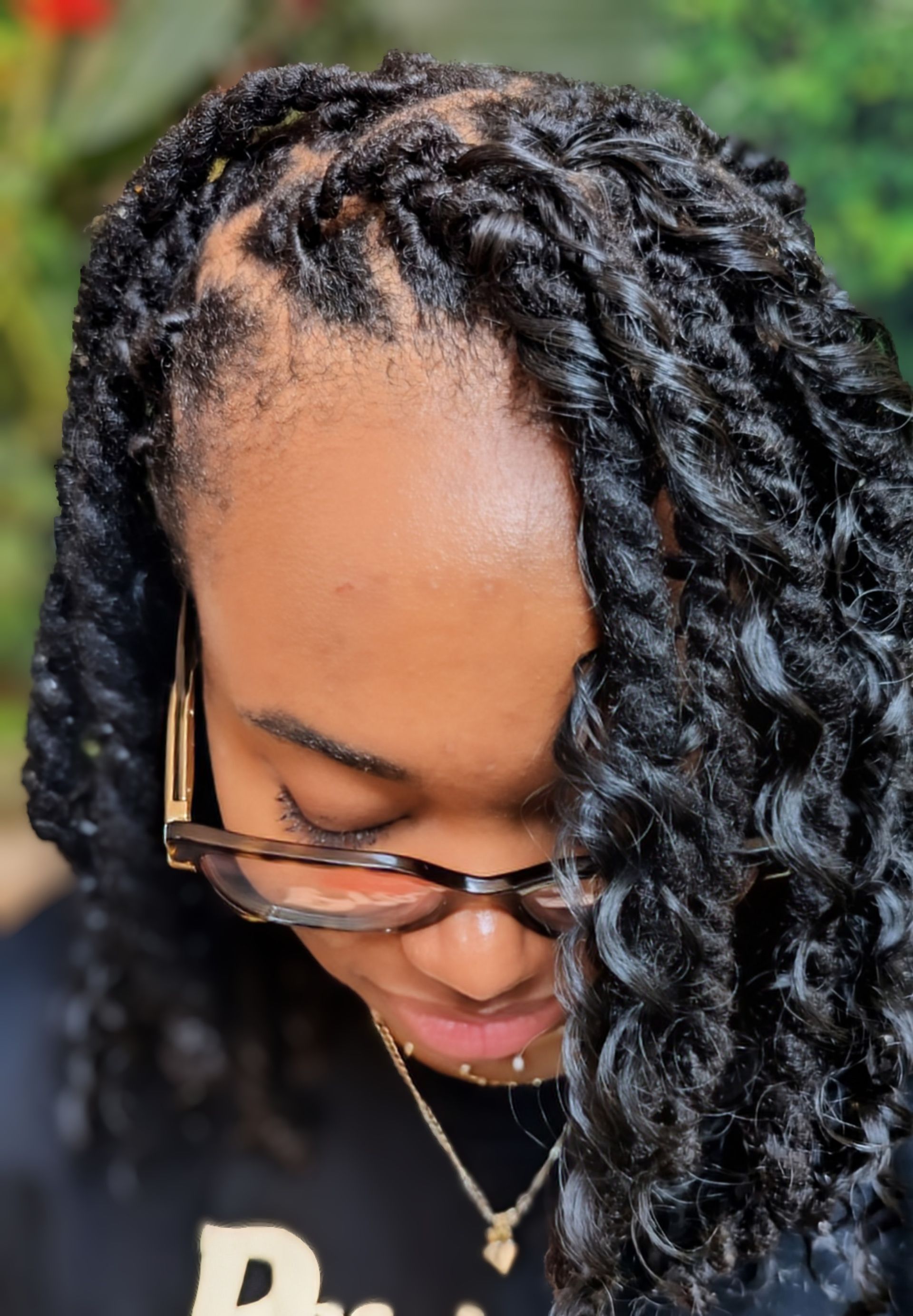 A person with dark, textured hair styled in shoulder-length twists, wearing tortoiseshell-rimmed glasses.