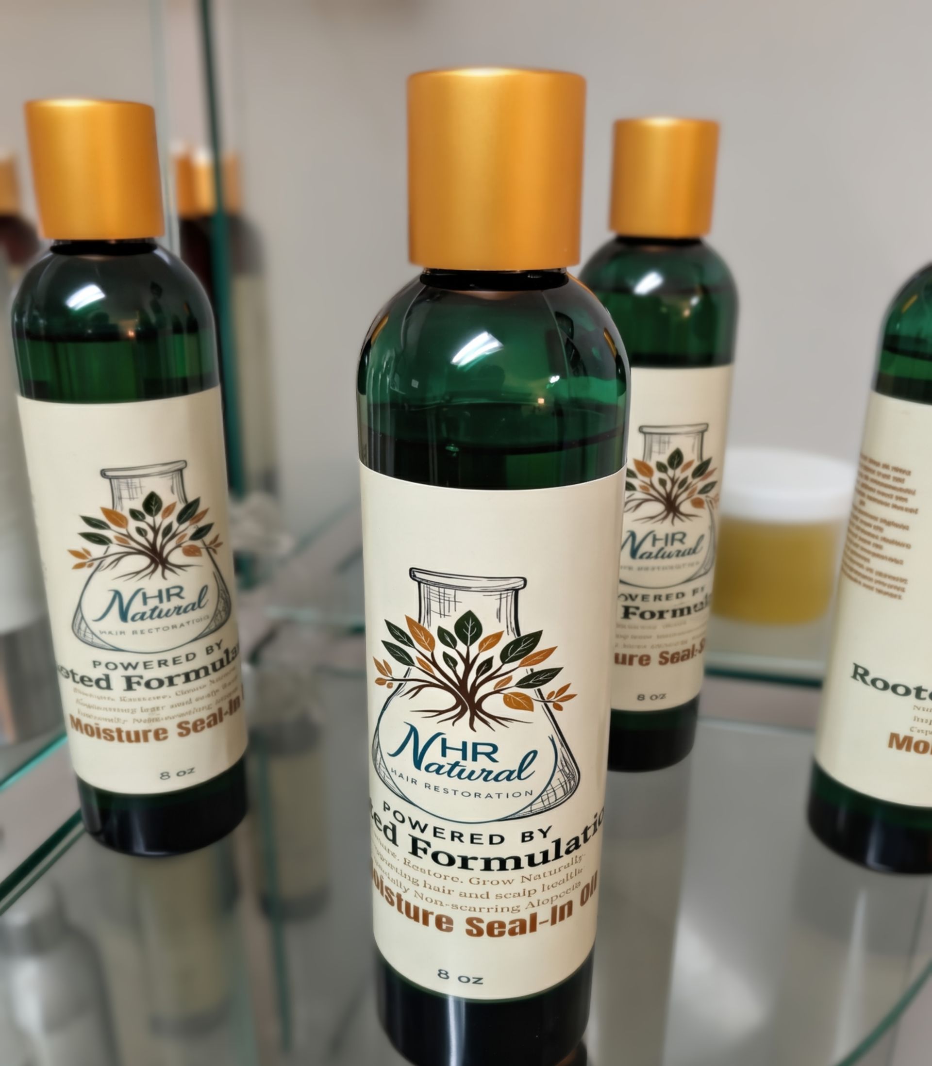 Green bottles of NR Naturals hair care oil with gold caps lined up on a glass shelf.