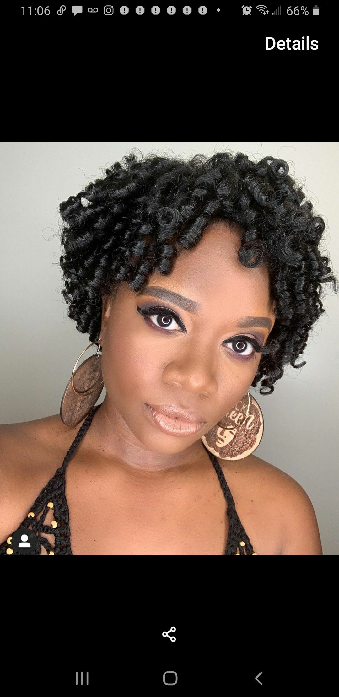 A person with short, dark, coiled hair and large, circular earrings against a neutral background.