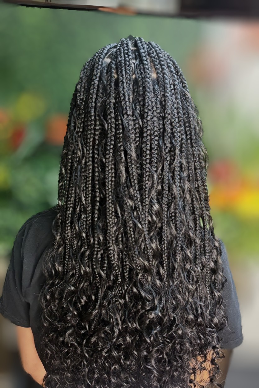A person seen from behind with long, dark, braided hair that transitions into loose, wavy curls at the ends.