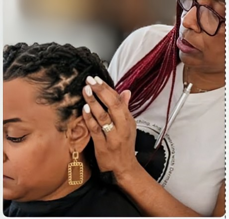 A stylist examines the scalp and braided hair of a client.