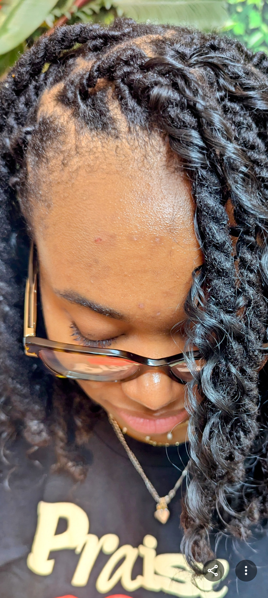 A person with long, dark, twisted hair style and glasses, seen from an overhead angle, looking down.