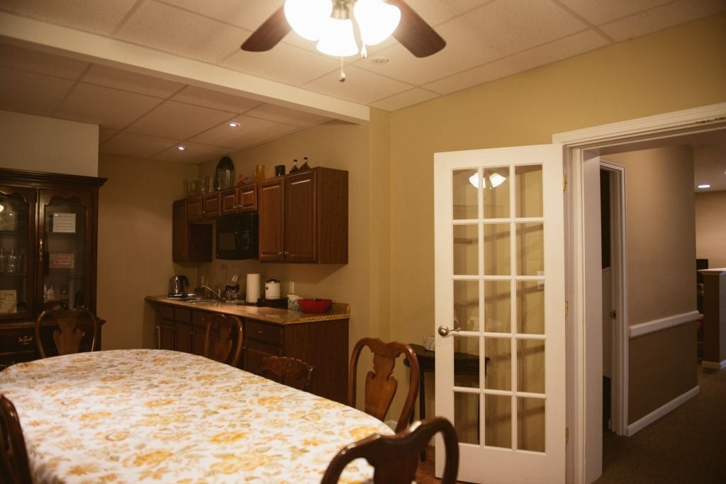 Dining room with table, chairs, wooden cabinets, ceiling fan, and open French doors to a hallway.
