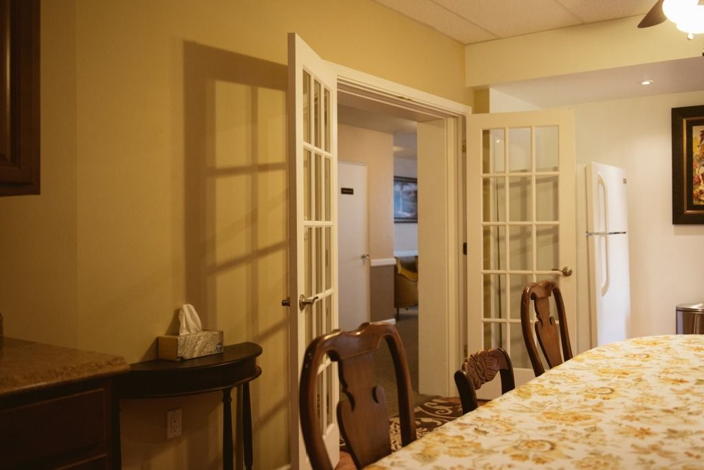 Dining room with wooden chairs, a long table, and open French doors leading to a hallway.