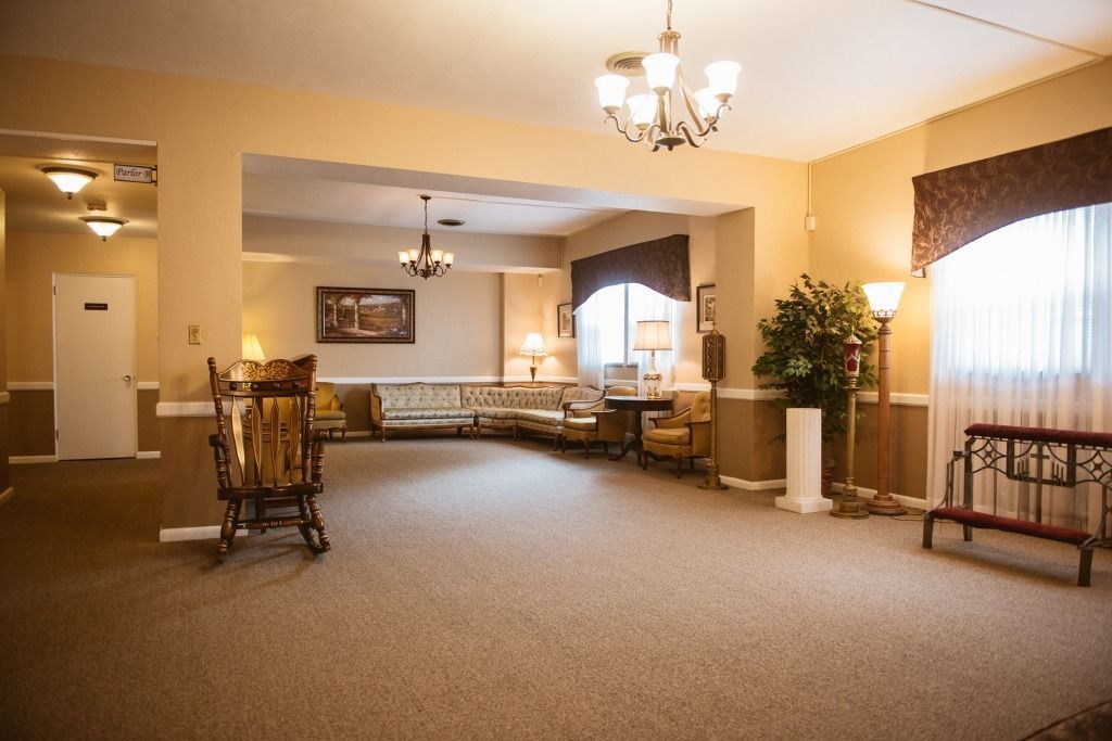 Spacious beige lobby with carpet, chandelier, seating, and large windows with curtains