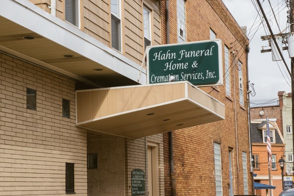 Green sign for Nathan Funeral Home on a brick building exterior.