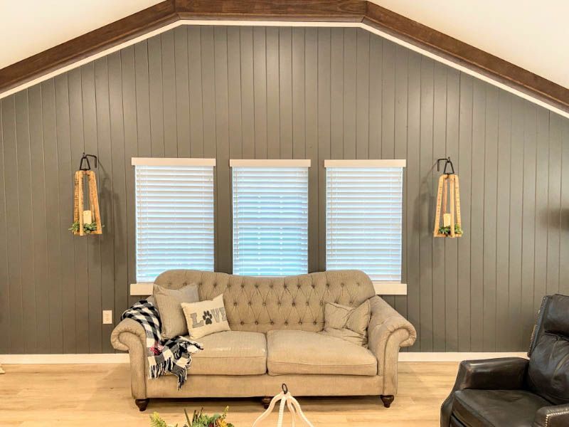 Love is Blinds CO: There is a couch and a chair in the living room, honeycomb shades on windows.