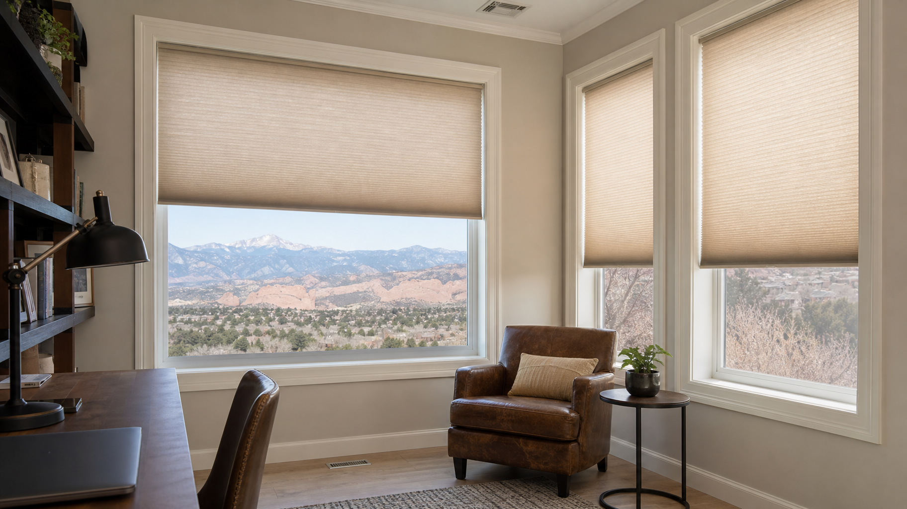 Bright living room with beige shades, large windows with honeycomb shades, and a tan chair overlooking a desert landscape.
