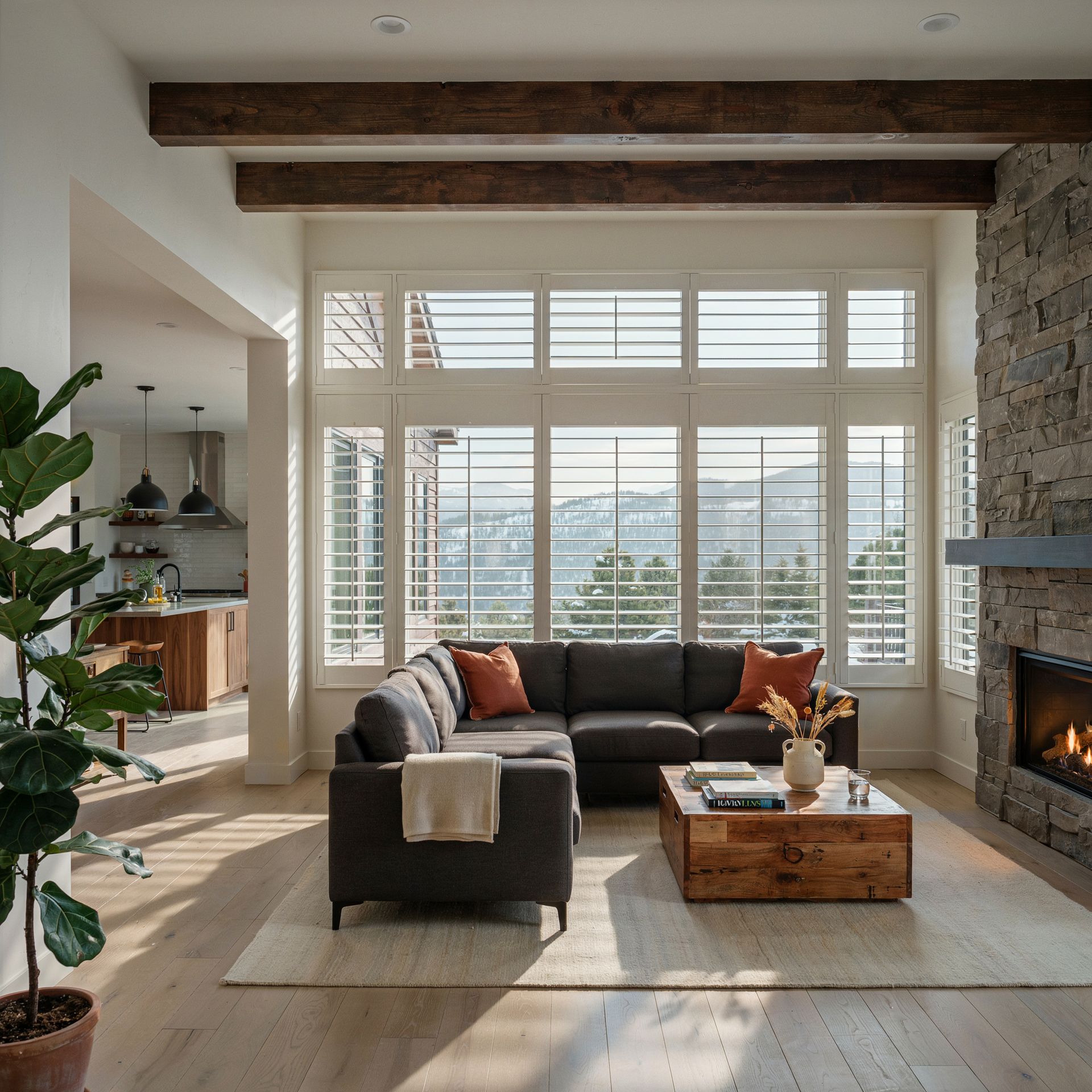 Modern living room with dark sectional, wood coffee table, large windows with shutters, and a fireplace.
