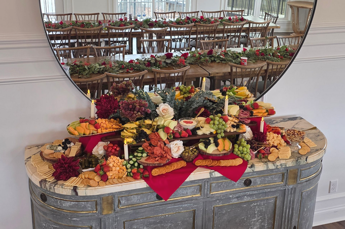 Elegant buffet table with assorted cheese, fruit, and charcuterie platters beneath a round mirror