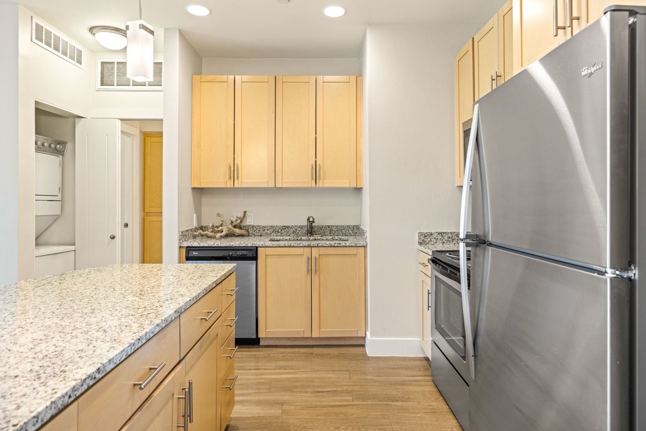Bright kitchen with granite countertops, light wood cabinets, and stainless-steel appliances.