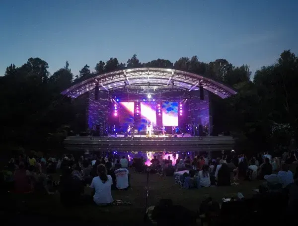 A crowd of people are sitting in front of a stage at a concert