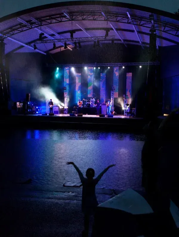 A little girl stands in front of a stage at a concert