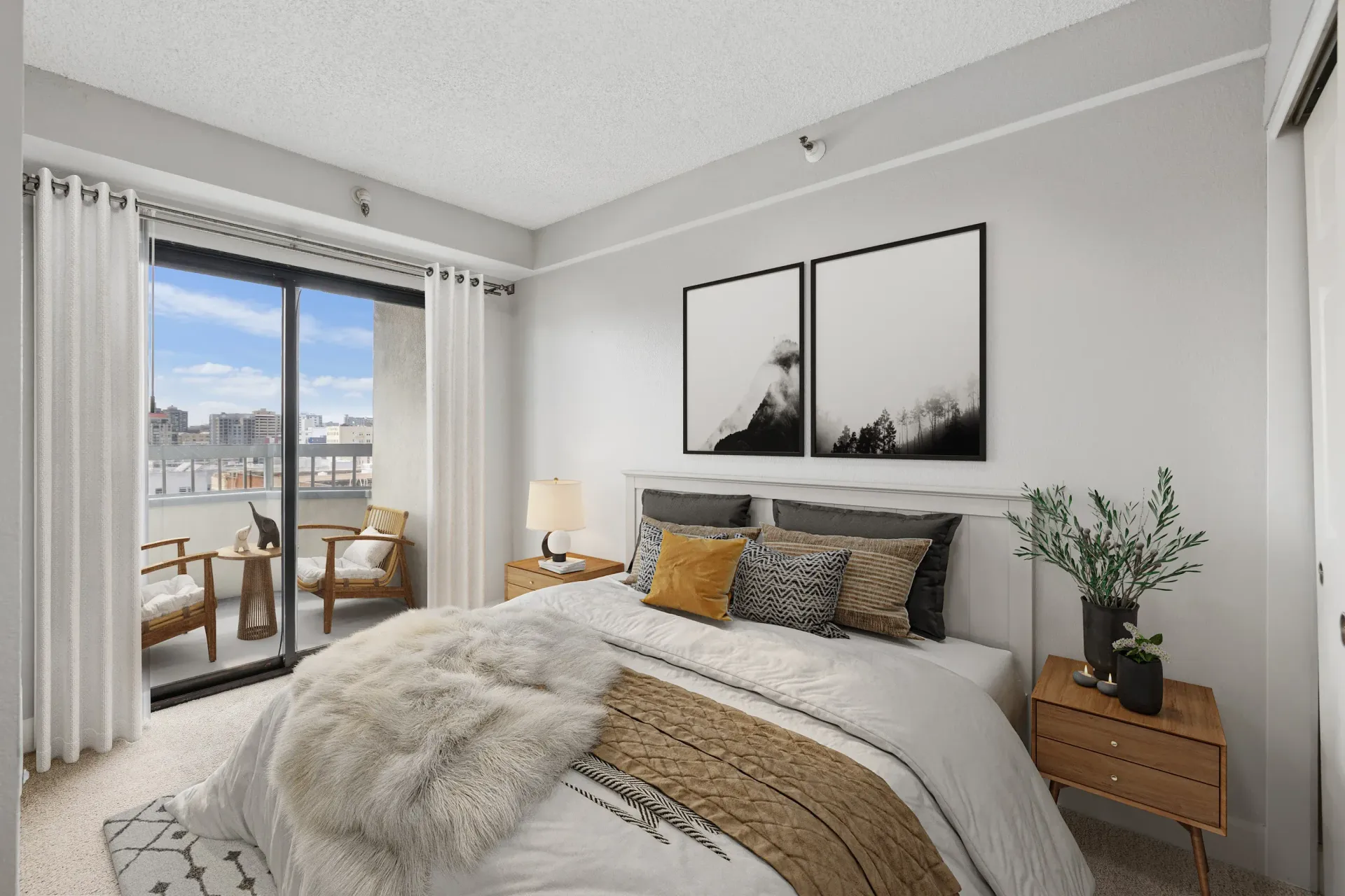 Bedroom with a white bed, gray accents, and sliding glass doors to a balcony at Tower 737, offering apartments in San Francisco, CA.