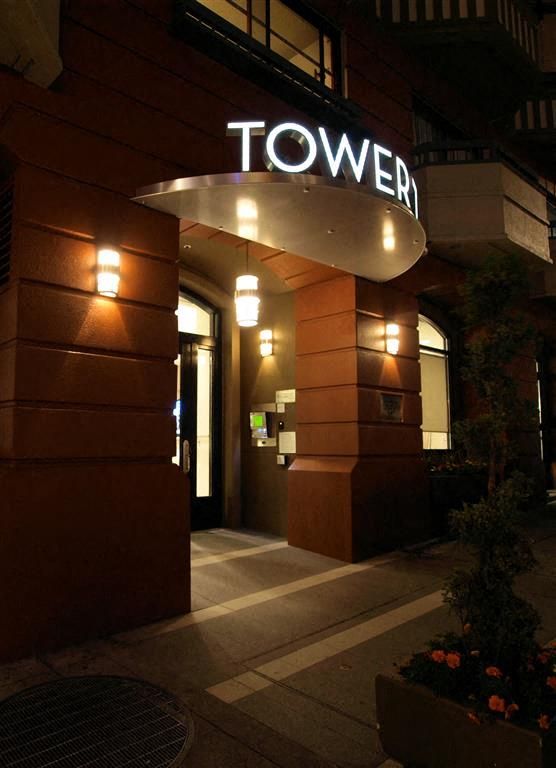 Night exterior of apartment building entrance with illuminated 'TOWER' sign.