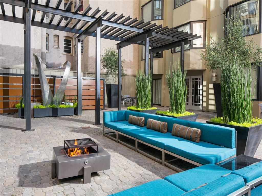 Outdoor courtyard with blue cushioned seating, planters, and a fire pit under a pergola at Tower 737, offering apartments in San Francisco, CA.