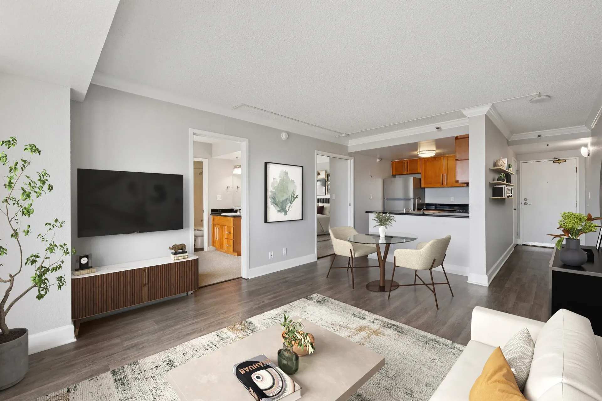 Open-concept living room with TV, dining table, and a kitchen in a modern apartment at Tower 737, offering apartments in San Francisco, CA.