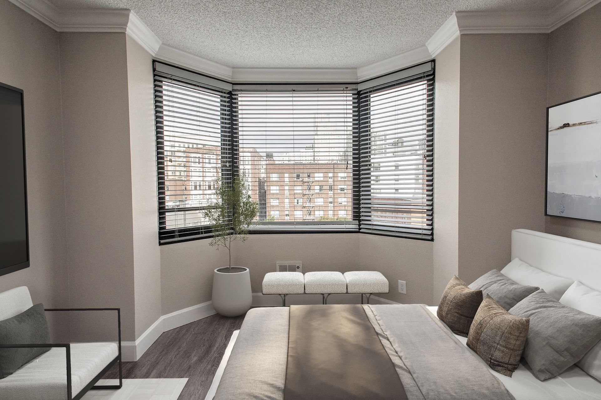Bedroom with a curved bay window, horizontal blinds, a bed with neutral linens, and a small bench at Tower 737, offering apartments in San Francisco, CA.