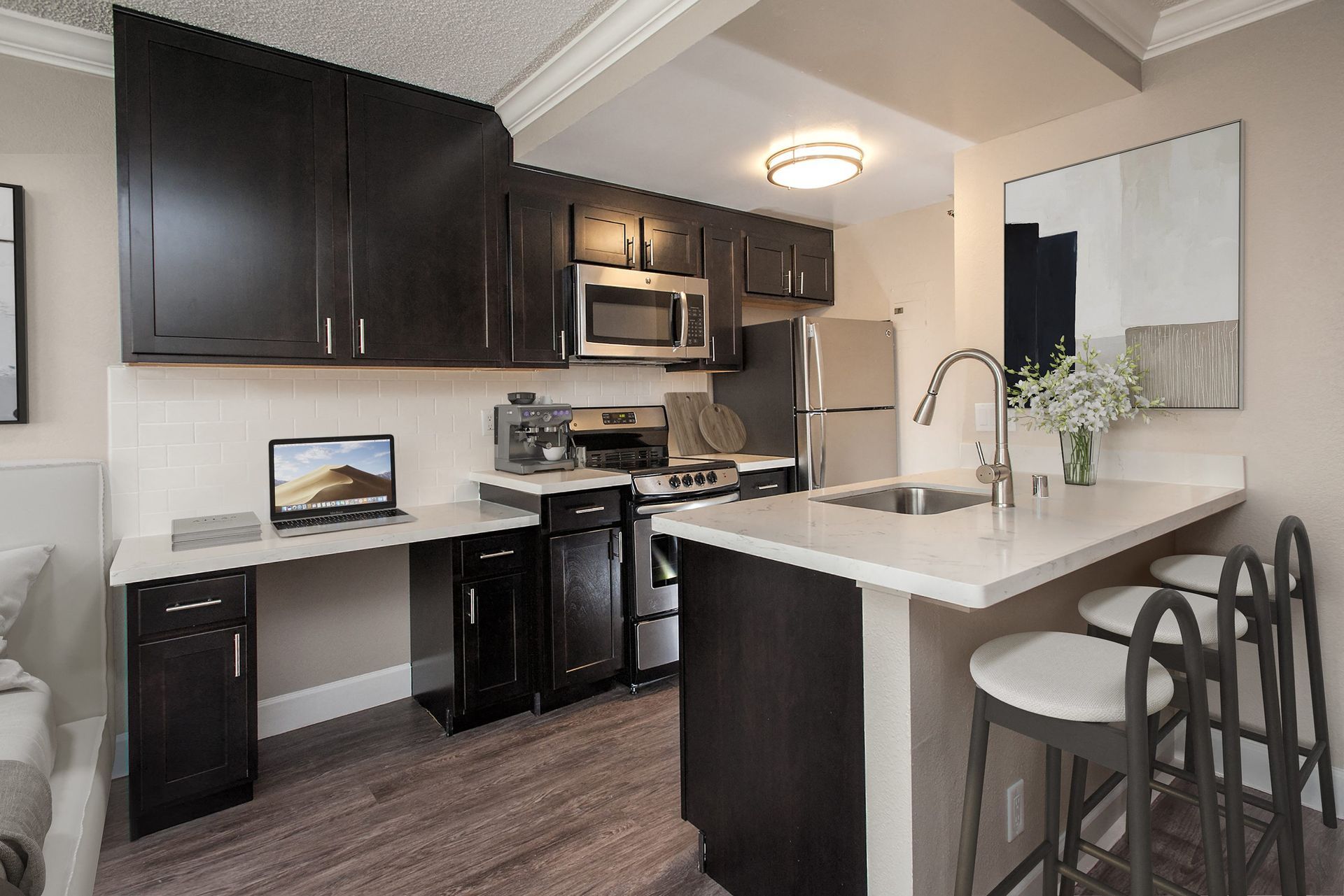 Modern apartment kitchen with dark wood cabinets, stainless steel appliances, and a bar-height island at Tower 737, offering apartments in San Francisco, CA.