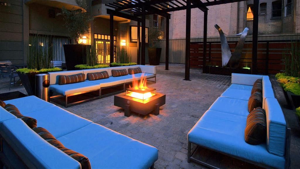 Outdoor seating area with blue cushions around a fire pit under a pergola at Tower 737, offering apartments in San Francisco, CA.