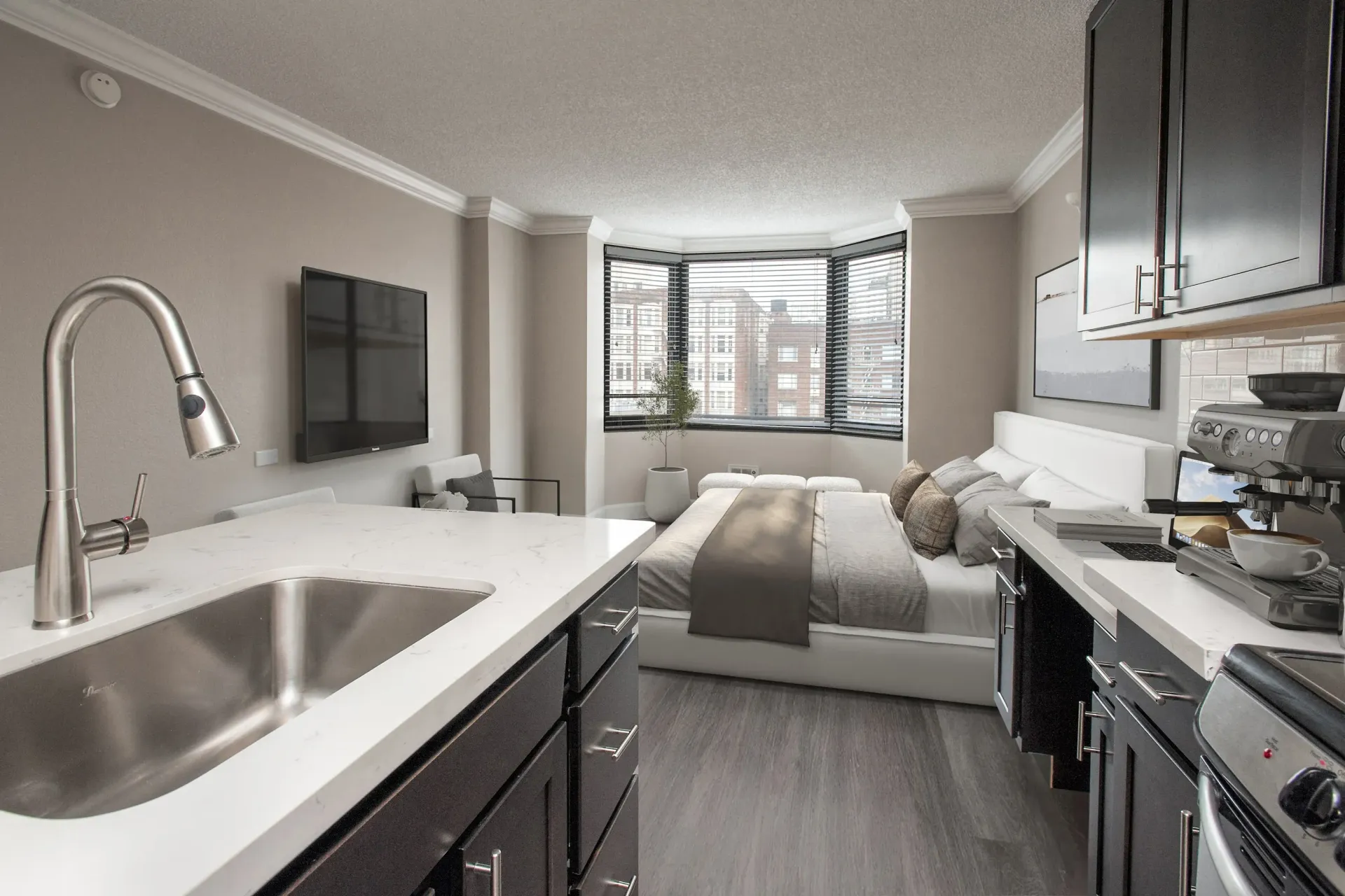 Open-concept kitchen and living area with a bed near a bay window and stainless sink at Tower 737, offering apartments in San Francisco, CA.