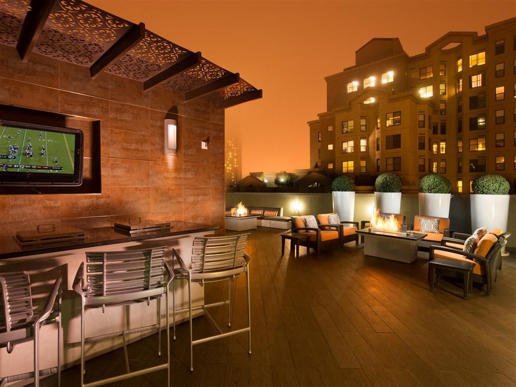 Rooftop lounge area with fire pits, sofas, and a wall-mounted TV on the left at Tower 737, offering apartments in San Francisco, CA.