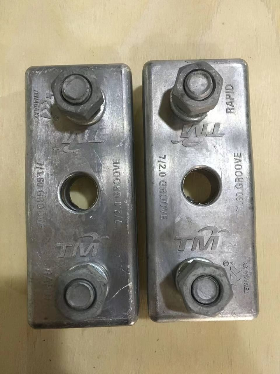 Two metal cable clamps with nuts and bolts, marked 