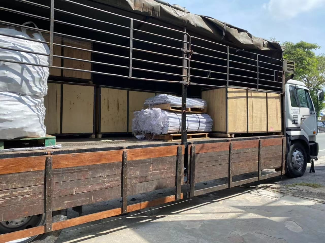 Truck loaded with various packaged items, including wooden crates and wrapped bundles, outdoors.
