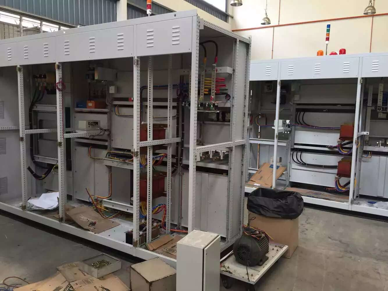 Electrical control cabinets in a workshop; gray metal with exposed wires and components.