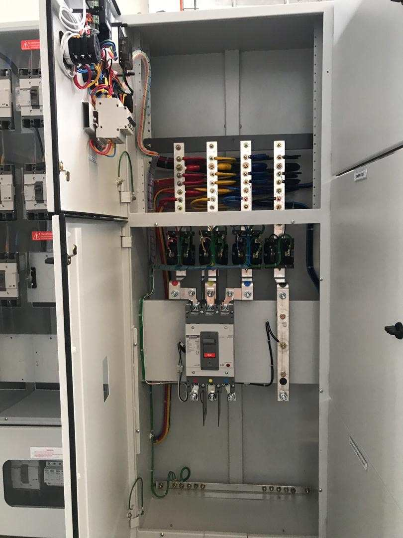 Open electrical panel with circuit breakers, wires, and connections.
